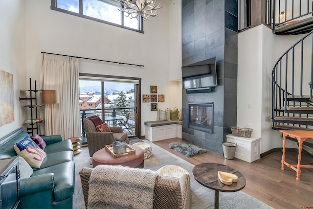 living room with baseboards, stairway, a tile fireplace, a towering ceiling, and wood finished floors