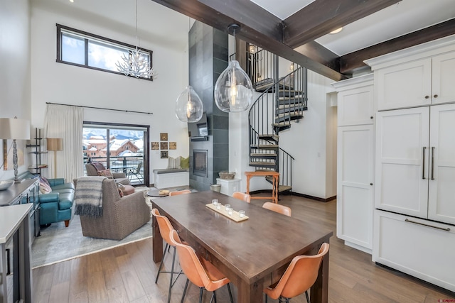 dining room featuring stairs, a high ceiling, a fireplace, and dark wood-style flooring