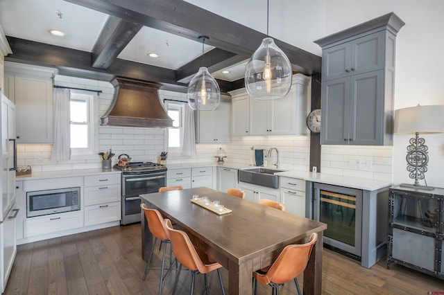 kitchen with dark wood finished floors, beverage cooler, appliances with stainless steel finishes, custom exhaust hood, and a sink