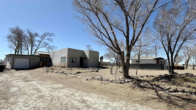 view of side of property featuring an attached garage and dirt driveway