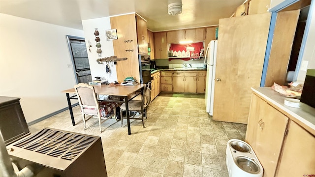 kitchen featuring freestanding refrigerator, dobule oven black, and a sink