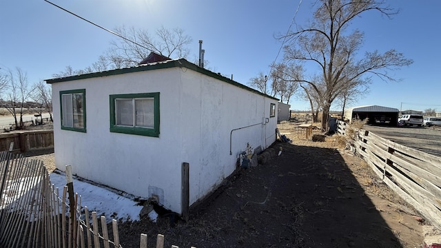 view of side of home featuring stucco siding and fence