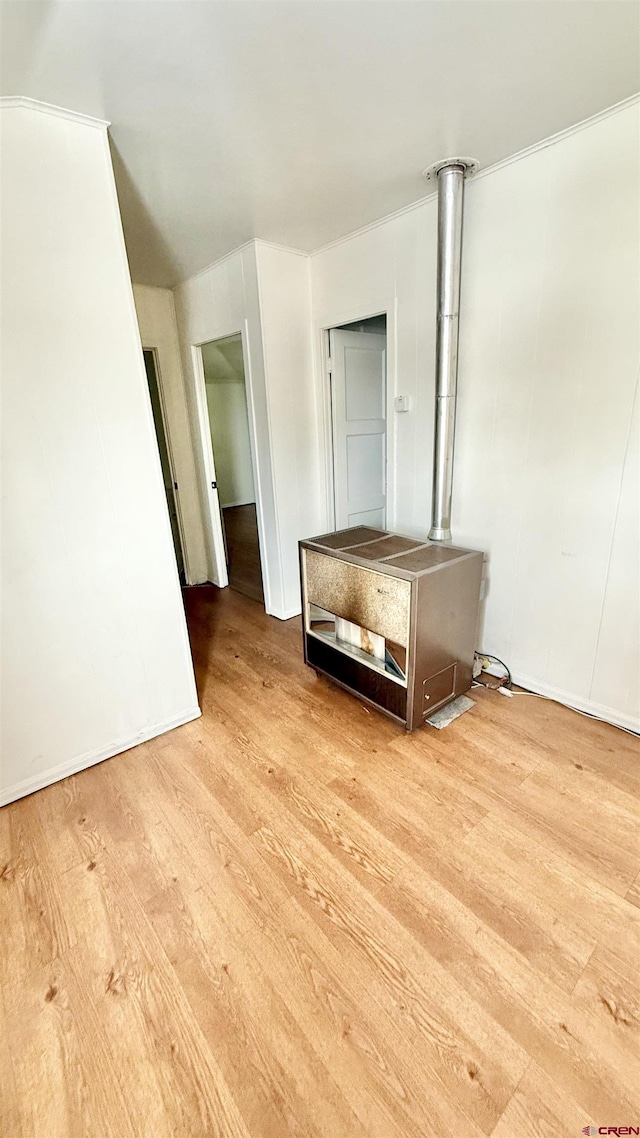 empty room featuring wood finished floors and a wood stove