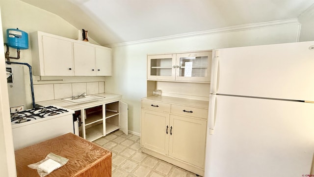 kitchen with light floors, light countertops, vaulted ceiling, white appliances, and a sink