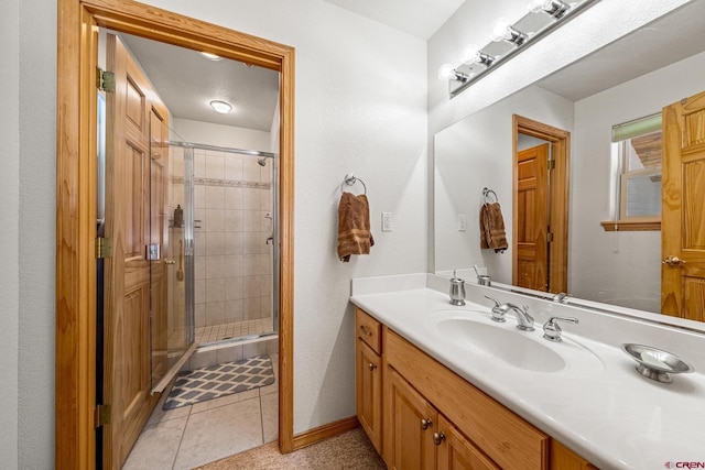 bathroom featuring tile patterned floors, a stall shower, vanity, and baseboards