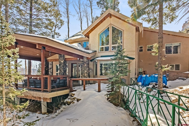 rear view of house with stucco siding and a wooden deck