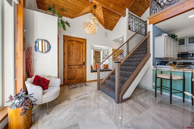 entrance foyer with baseboards, stairs, wooden ceiling, marble finish floor, and high vaulted ceiling