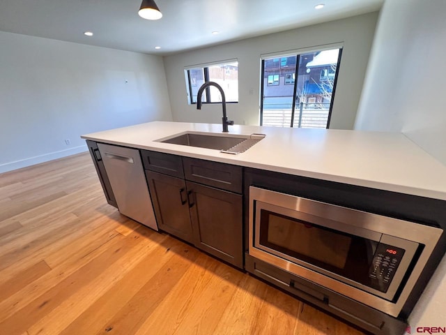 kitchen featuring light wood-style flooring, recessed lighting, a sink, stainless steel appliances, and light countertops