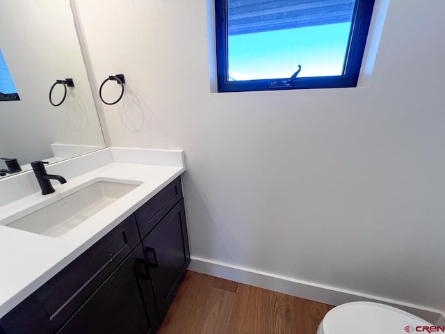 bathroom featuring toilet, vanity, baseboards, and wood finished floors