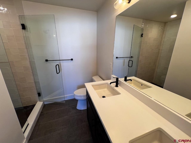 bathroom featuring a shower stall, toilet, double vanity, and a sink