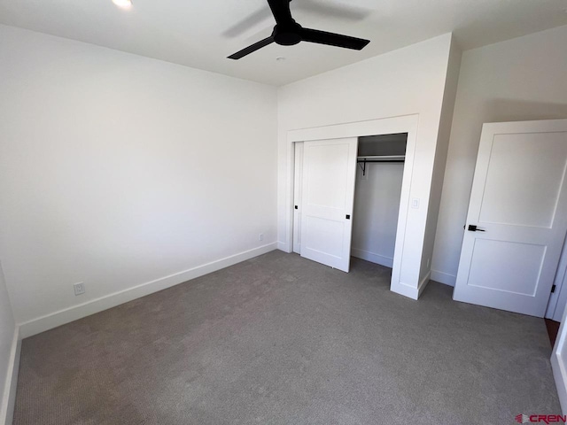 unfurnished bedroom with dark colored carpet, a closet, baseboards, and a ceiling fan