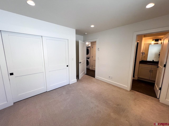 unfurnished bedroom with stacked washer and dryer, recessed lighting, a closet, and light carpet