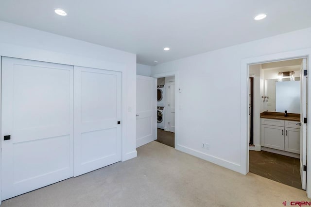 unfurnished bedroom featuring recessed lighting, light colored carpet, a closet, and stacked washing maching and dryer