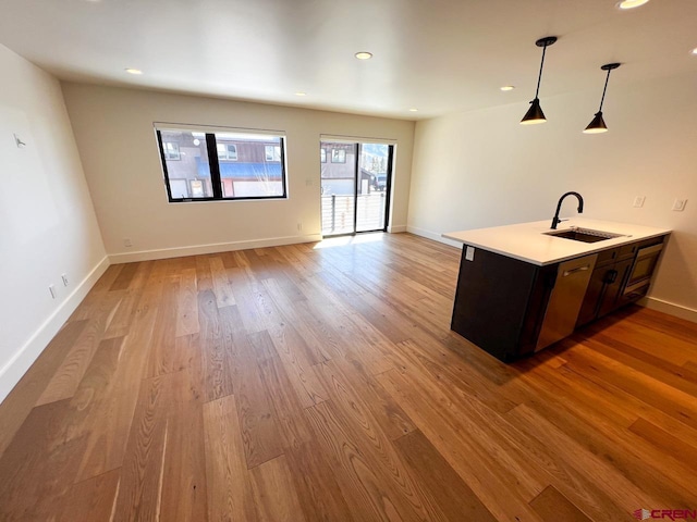 kitchen with wood finished floors, baseboards, a sink, light countertops, and pendant lighting