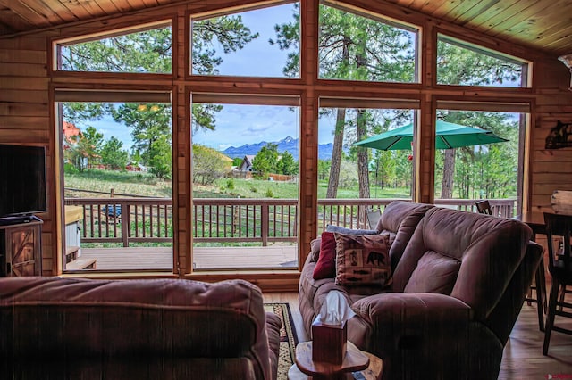 living area with wood walls, a mountain view, wood ceiling, and lofted ceiling