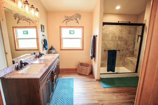 full bath featuring a sink, a stall shower, a healthy amount of sunlight, and wood finished floors