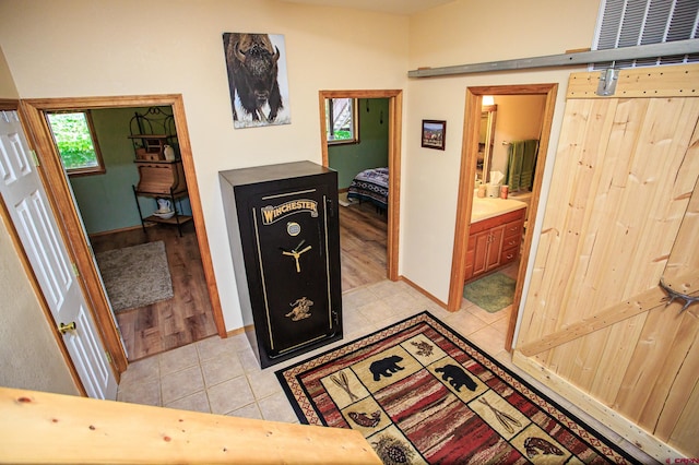 hallway featuring light tile patterned floors, a barn door, and baseboards