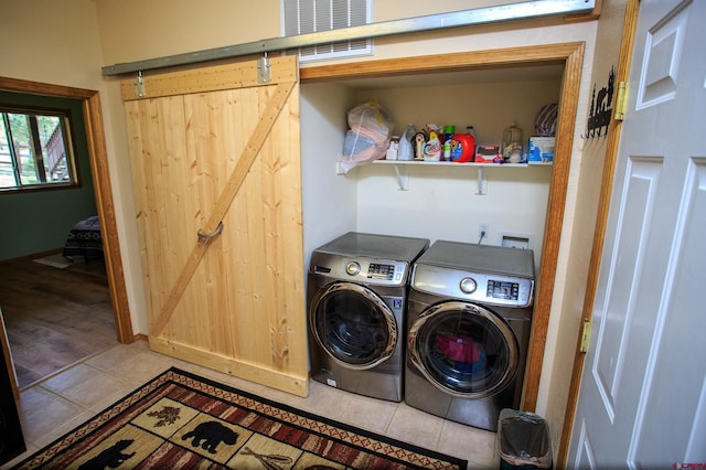 laundry room featuring light tile patterned floors, visible vents, laundry area, separate washer and dryer, and a barn door