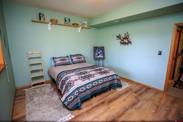 bedroom with wood finished floors, visible vents, and baseboards