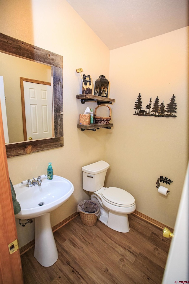 bathroom with a sink, toilet, baseboards, and wood finished floors