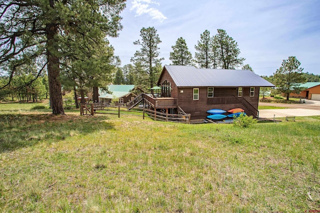 back of house featuring fence, stairway, a lawn, metal roof, and a deck