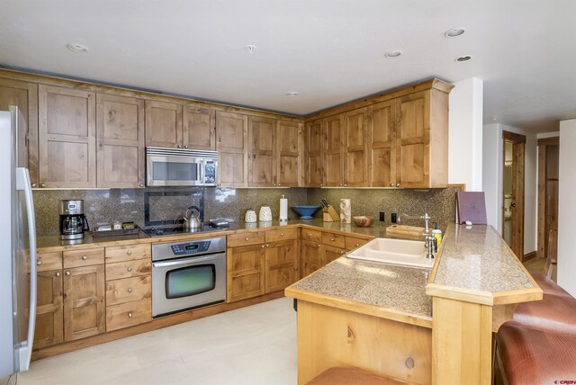 14 Hunter Hill Rd Unit C302, Mount Crested Butte, CO 81225 - kitchen with a kitchen bar, decorative backsplash, a peninsula, stainless steel appliances, and a sink