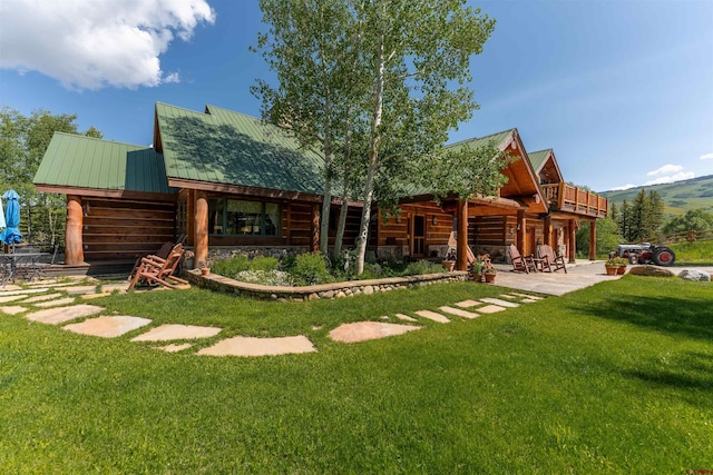 back of house featuring a patio, a lawn, and metal roof