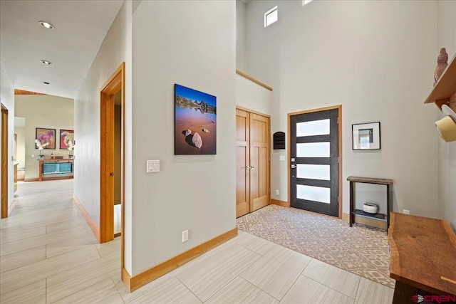foyer featuring baseboards and a high ceiling