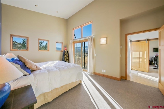 carpeted bedroom featuring access to exterior, baseboards, a high ceiling, and a barn door