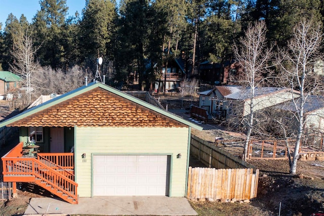 view of front facade featuring a garage, covered porch, and fence