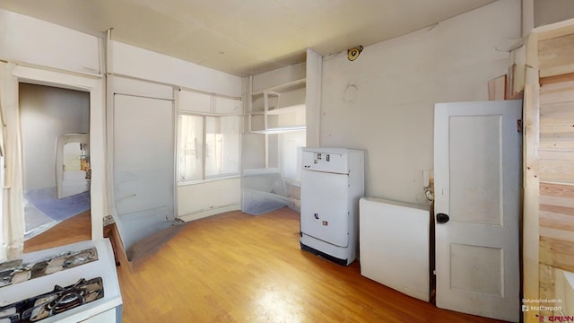 kitchen featuring light wood-type flooring, freestanding refrigerator, and open shelves