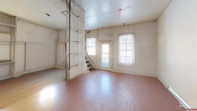 empty room with stairs, light wood-style flooring, and baseboards