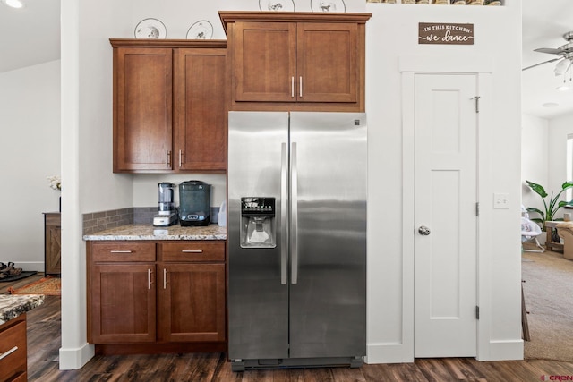 kitchen featuring dark wood finished floors, brown cabinetry, stainless steel fridge with ice dispenser, and light stone countertops