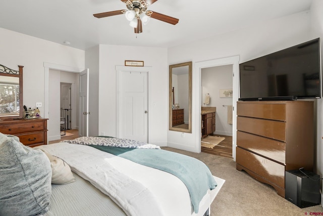 bedroom with baseboards, light carpet, ceiling fan, and ensuite bathroom