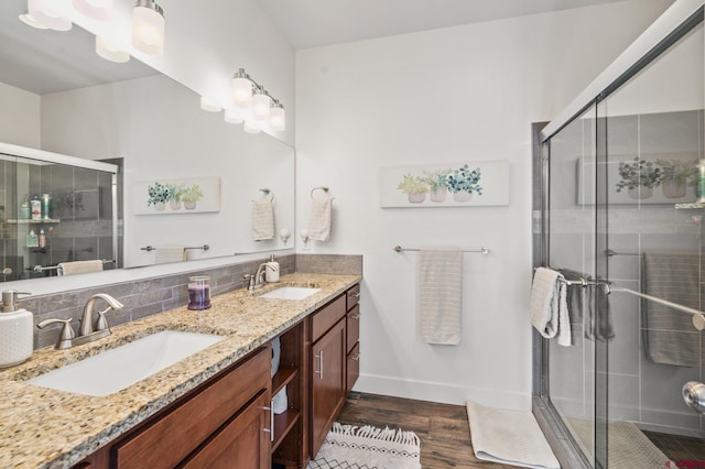 bathroom with double vanity, wood finished floors, a stall shower, and a sink