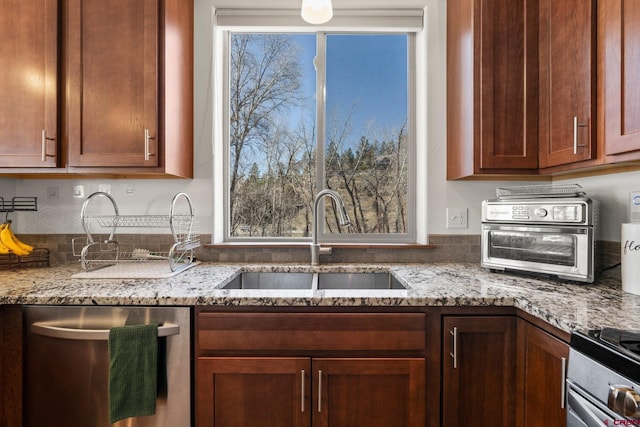 kitchen featuring a sink, light stone countertops, appliances with stainless steel finishes, and a toaster