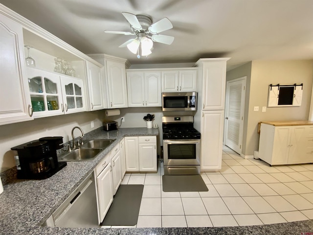 kitchen featuring ceiling fan, light tile patterned floors, stainless steel appliances, white cabinetry, and a sink