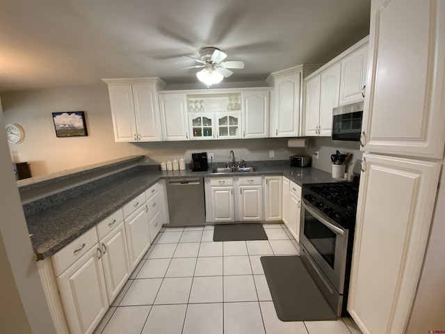 kitchen with light tile patterned floors, a peninsula, stainless steel appliances, a ceiling fan, and a sink