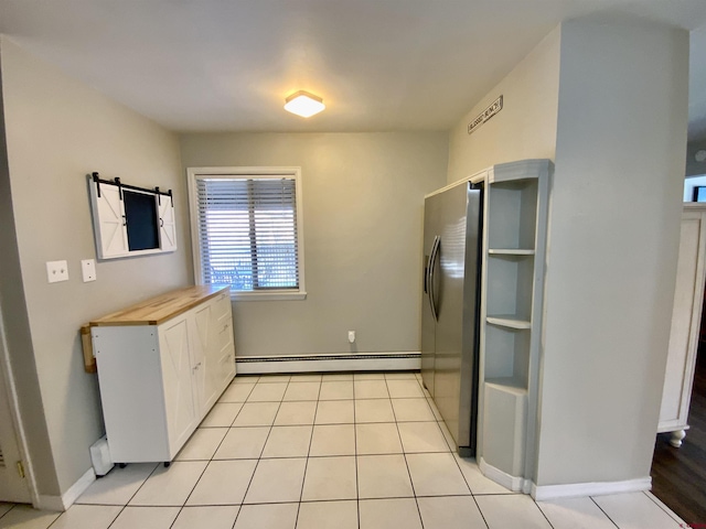 kitchen featuring butcher block countertops, light tile patterned floors, white cabinets, stainless steel fridge, and a baseboard radiator