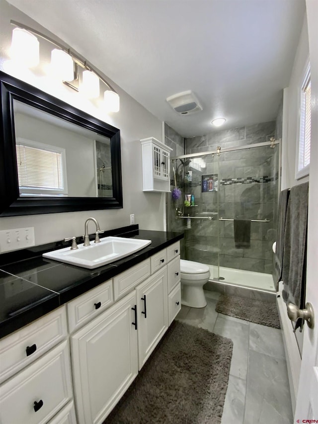 full bath with a stall shower, toilet, and vanity