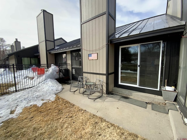 exterior space featuring a standing seam roof, a patio area, fence, and metal roof