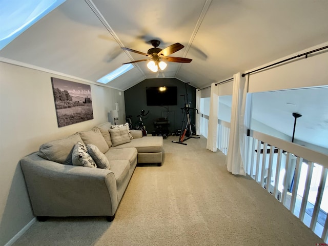 living area with vaulted ceiling with skylight, light colored carpet, and a ceiling fan