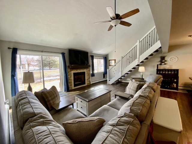 living area featuring dark wood finished floors, stairs, vaulted ceiling, a fireplace, and a ceiling fan