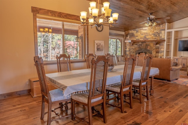 dining room with built in features, wood-type flooring, a stone fireplace, wooden ceiling, and baseboards