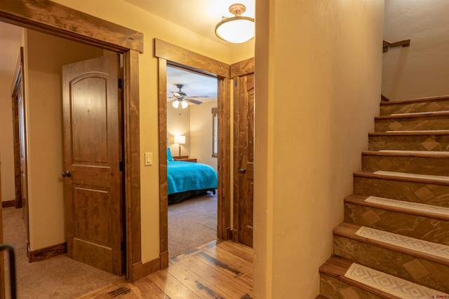 staircase with a ceiling fan, wood finished floors, and baseboards