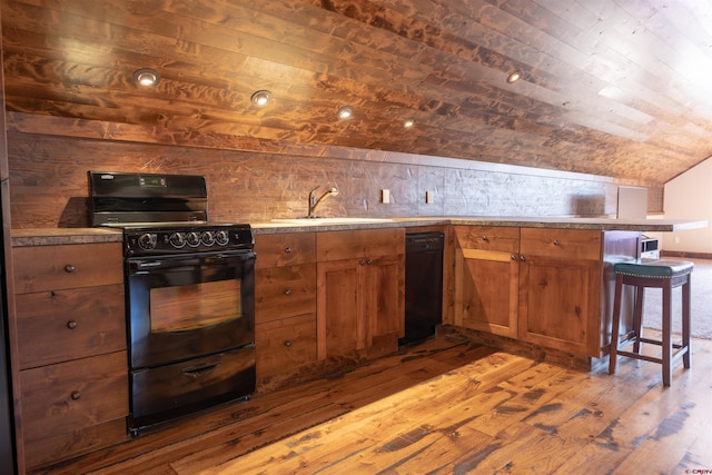 kitchen featuring a sink, black appliances, vaulted ceiling, wood-type flooring, and brown cabinets