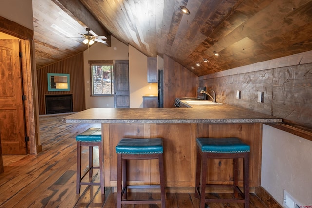 bar with dark wood finished floors, vaulted ceiling with beams, a fireplace, a sink, and wooden ceiling