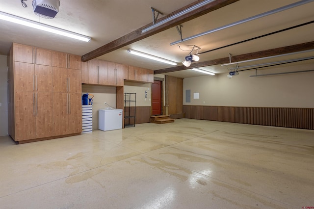 garage with electric panel, a garage door opener, and wainscoting