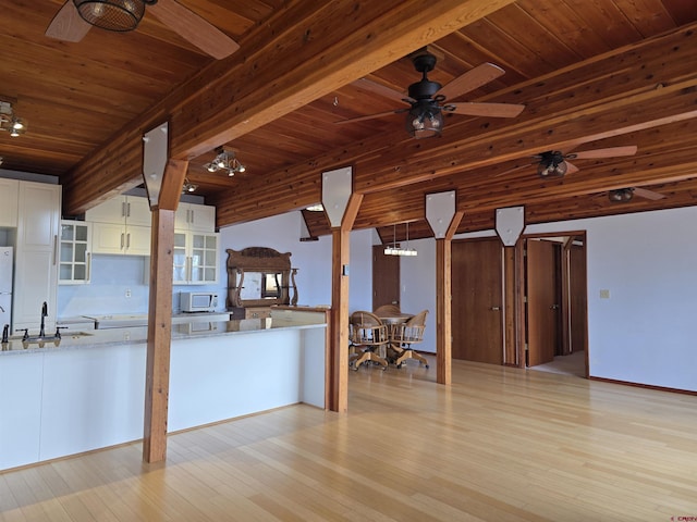 kitchen with white appliances, beam ceiling, a sink, white cabinetry, and light wood-type flooring