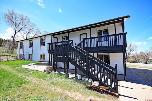 back of house featuring stairway, a yard, and covered porch